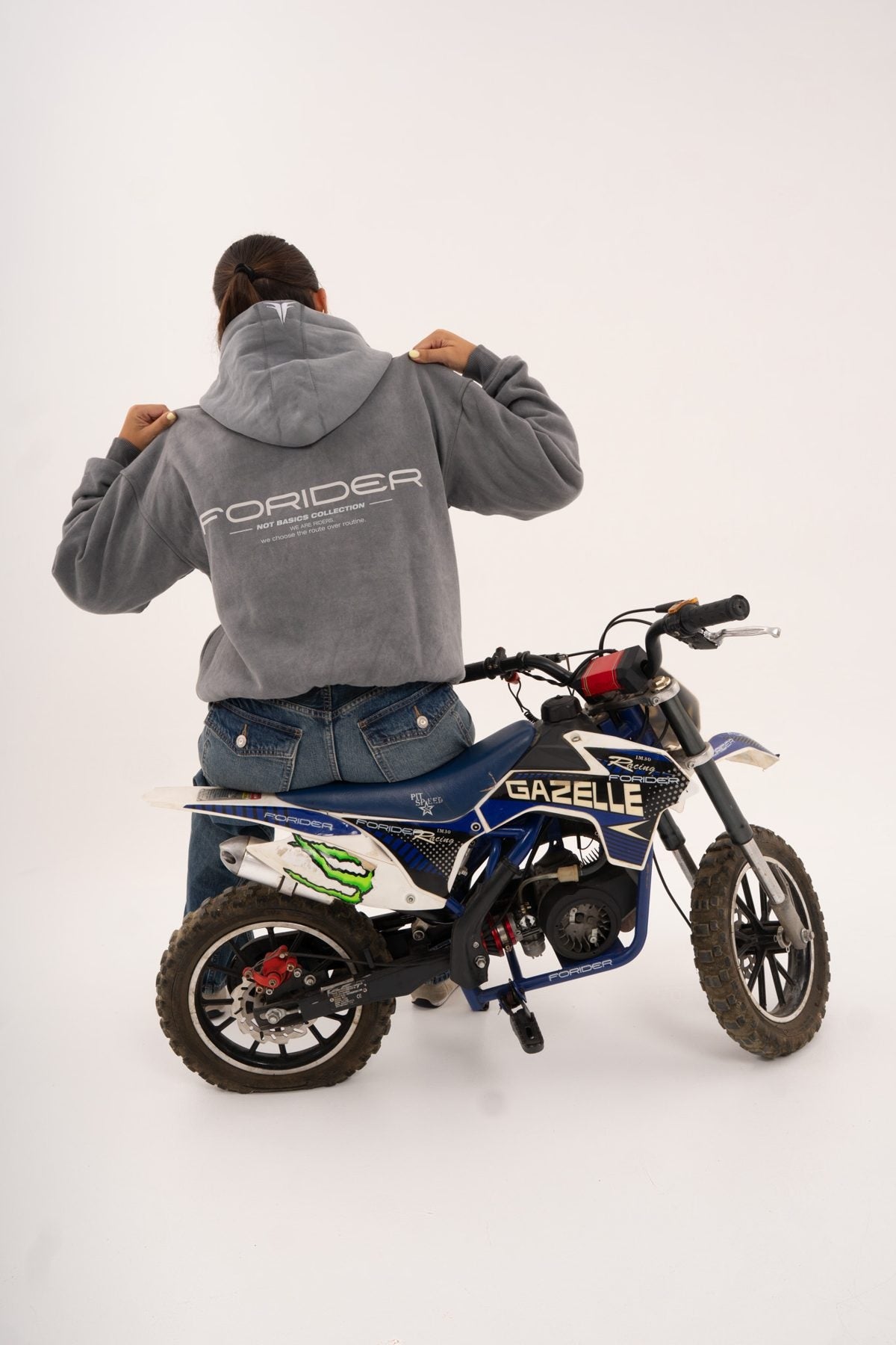 Rider de espaldas sobre una moto tirando de la sudadera gris
