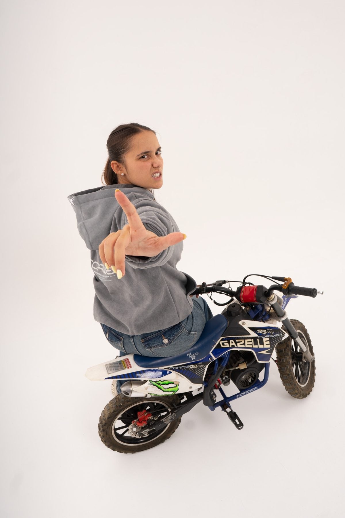 Rider sobre una moto señalando con la sudadera gris