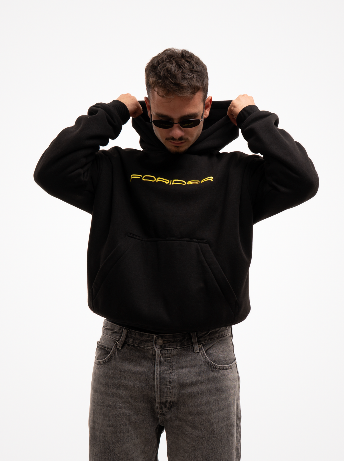 Hombre subiéndose la capucha de la sudadera de moto negra FORIDER, con el logotipo amarillo en el pecho