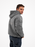 Hombre con la sudadera de moto gris washed mirando por encima del hombro, con el estampado FORIDER en la espalda
