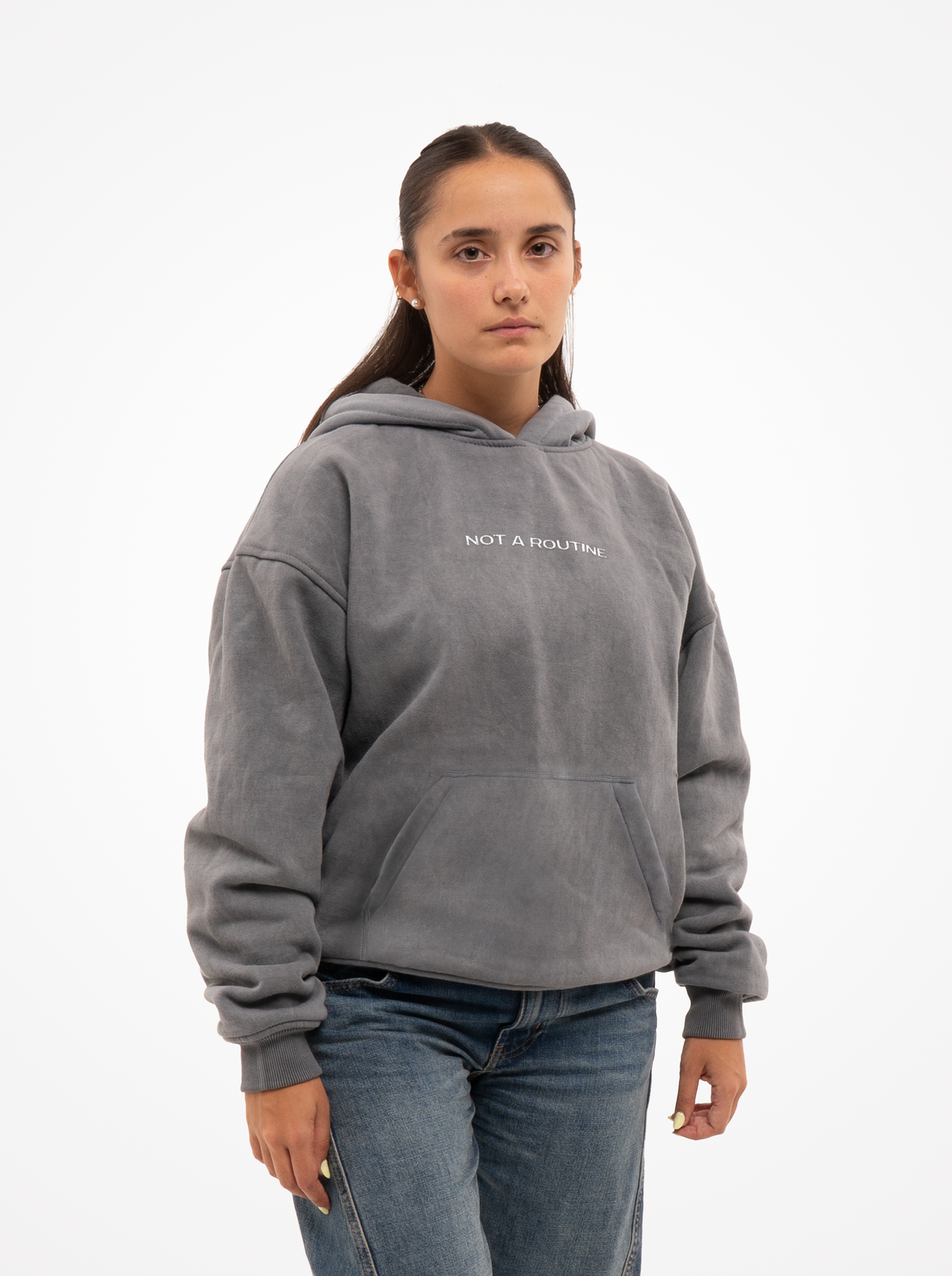 Mujer con la sudadera de moto gris washed Not a Routine, vista frontal con capucha y vaqueros