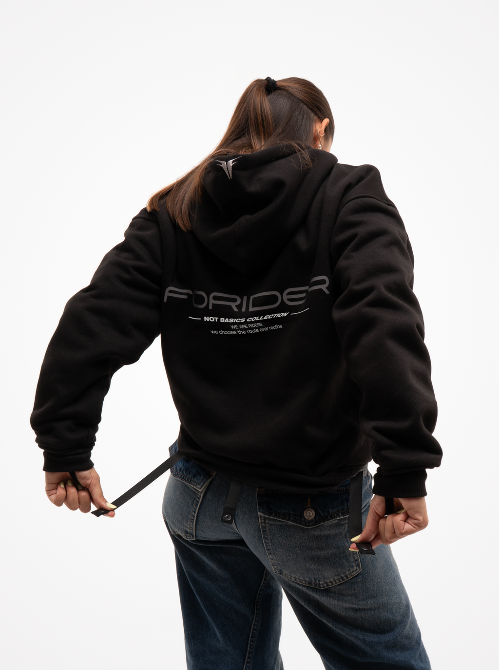 Mujer de espaldas con la sudadera de moto negra Not a Routine, capucha con logotipo y estampado FORIDER en la espalda