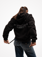 Mujer de espaldas con la sudadera de moto negra Not a Routine, capucha con logotipo y estampado FORIDER en la espalda