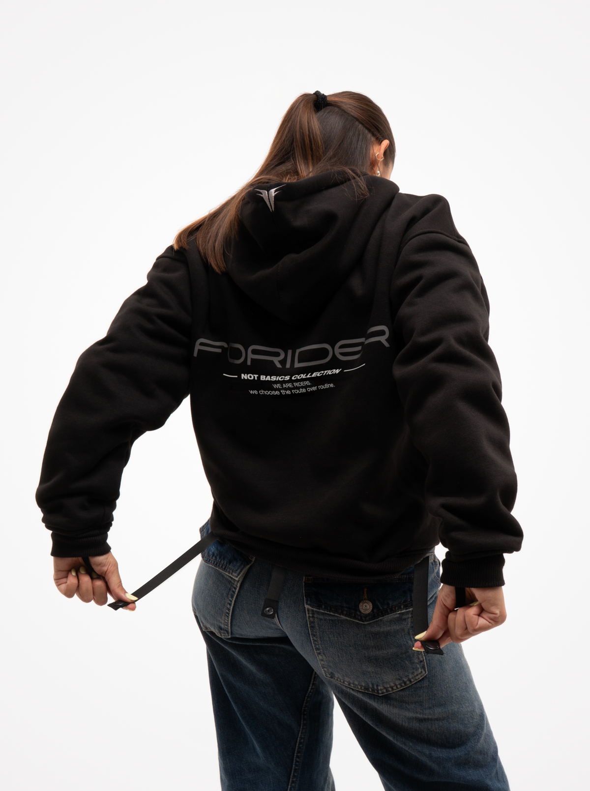 Mujer de espaldas con la sudadera de moto negra Not a Routine, capucha con logotipo y estampado FORIDER en la espalda