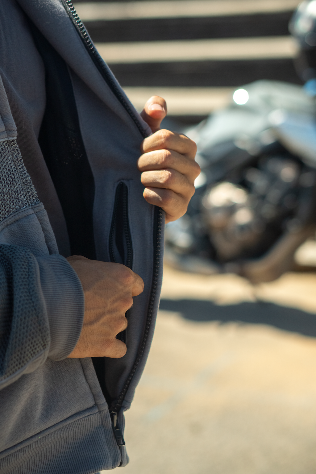 Pormenor do bolso interior com fecho do casaco de moto de verão, com a mota ao fundo