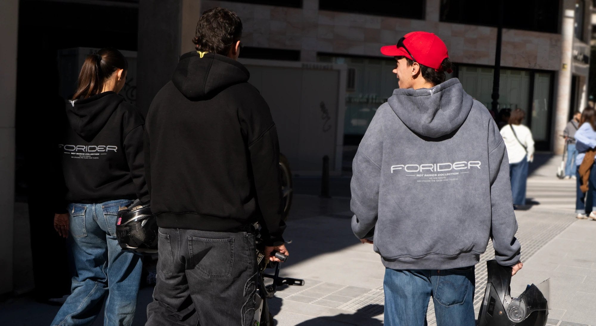 Tres riders con sudaderas FORIDER caminando por la calle