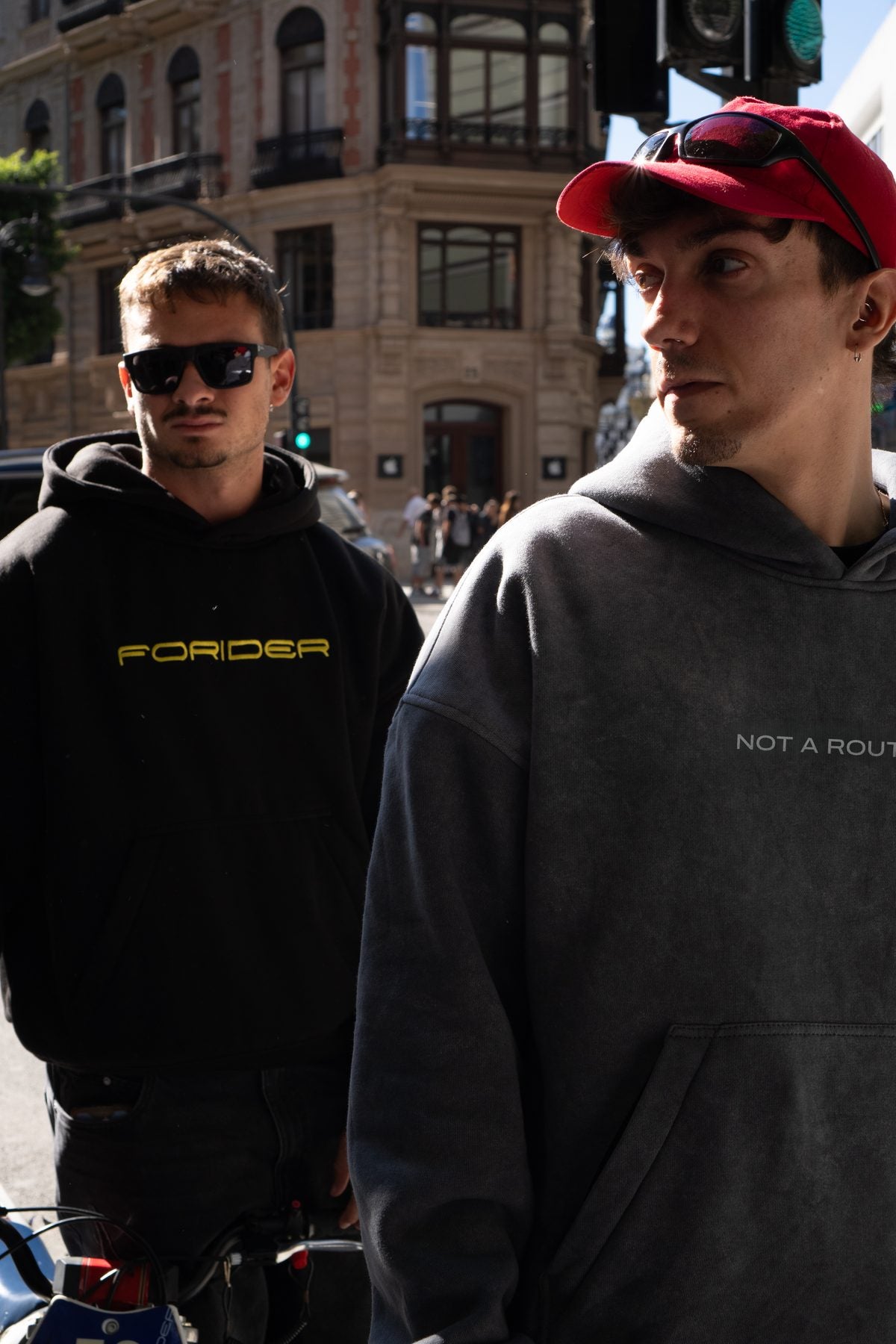 Dos riders con sudaderas negra y gris en la esquina de una calle
