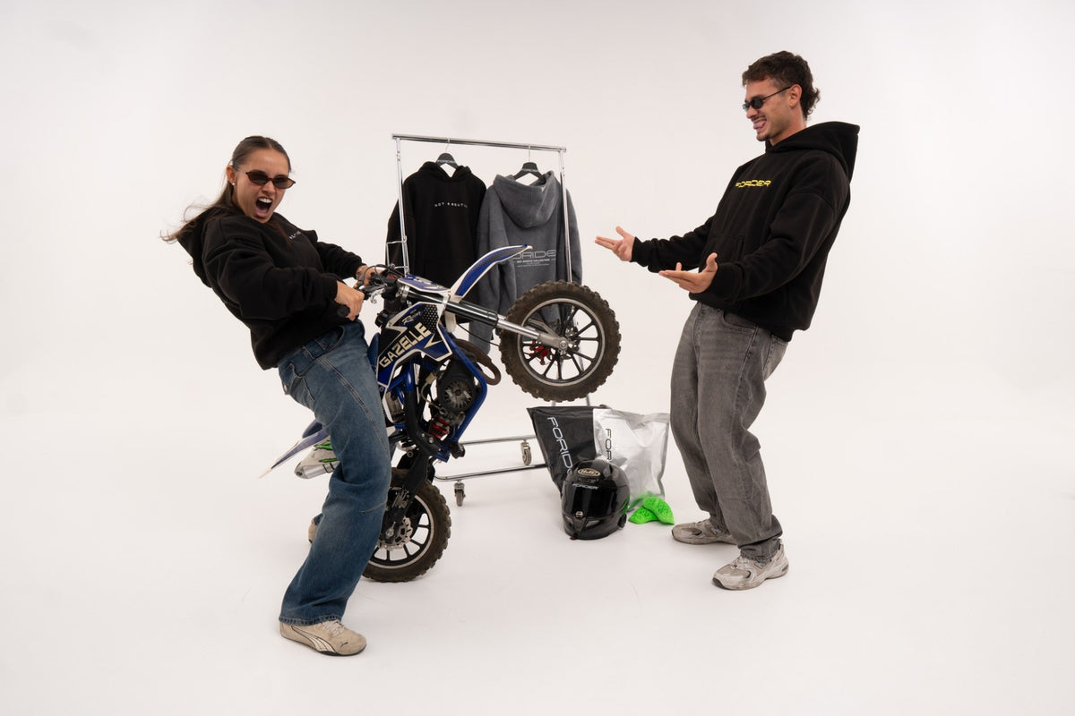 Dos riders jugando con una moto en el estudio